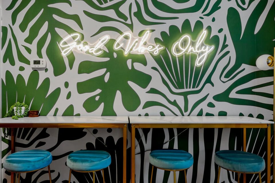 Sip cocktails under the glowing neon sign in this vibrant bar-style nook with plush seating.