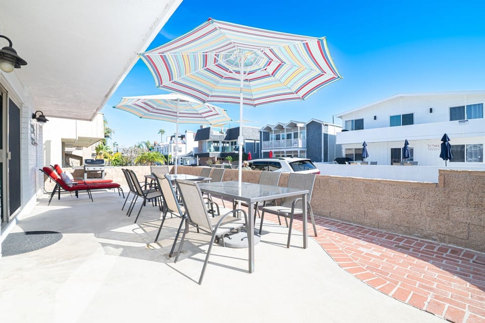 The front patio area includes outdoor dining table with seating, market umbrellas, and propane gas grill for sunset cookouts.
                