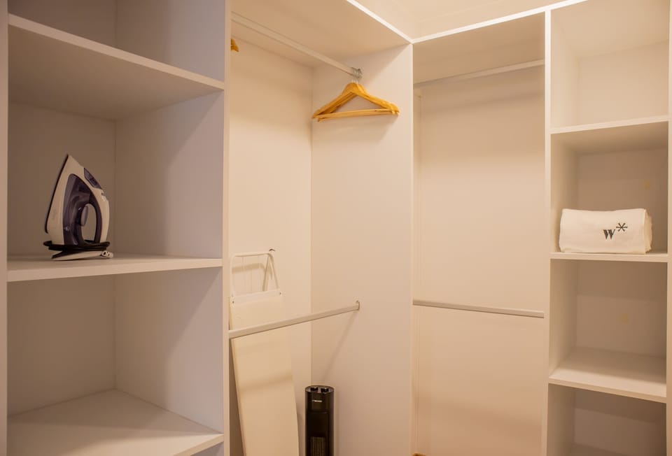 Walk-in closet with shelves, hanging space, and ironing board.