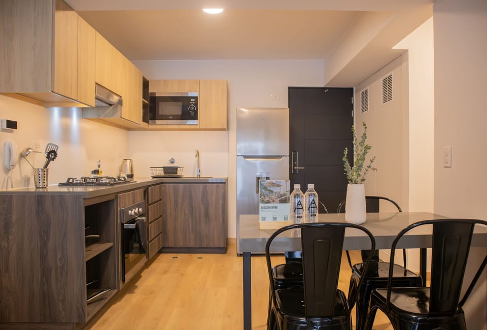 Open kitchen and dining area with wooden cabinets and black chairs.
