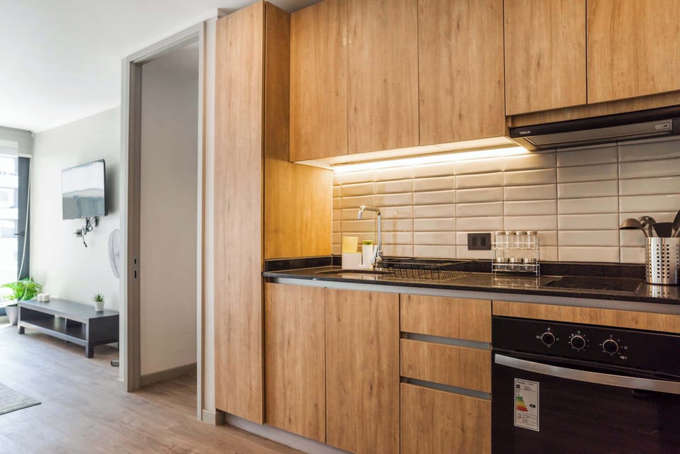 Sleek and modern kitchen with stylish wooden cabinets and a cozy adjacent living area, perfect for relaxing after a day of exploring.