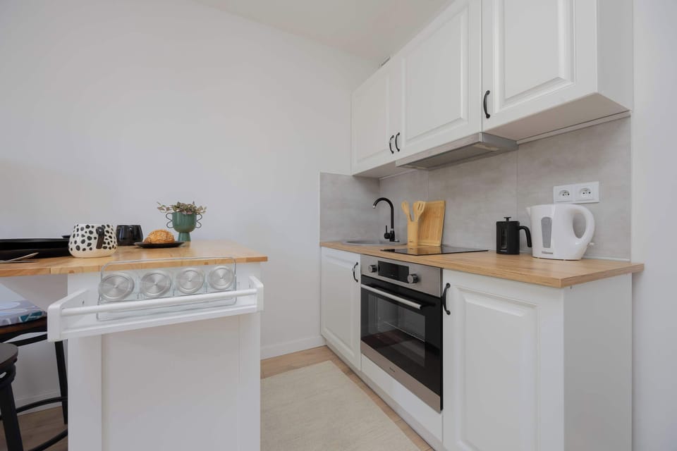 A compact kitchen with white cabinetry and full equipment makes meal preparation easy in a homely atmosphere.