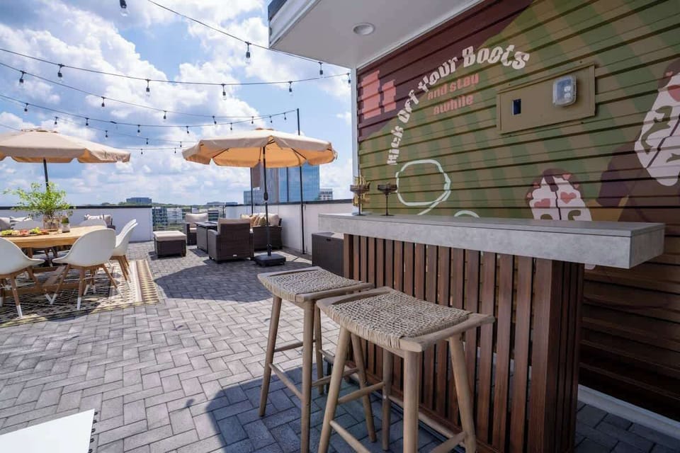 Rooftop bar with a green plank wall, string lights, and bar stools in daylight