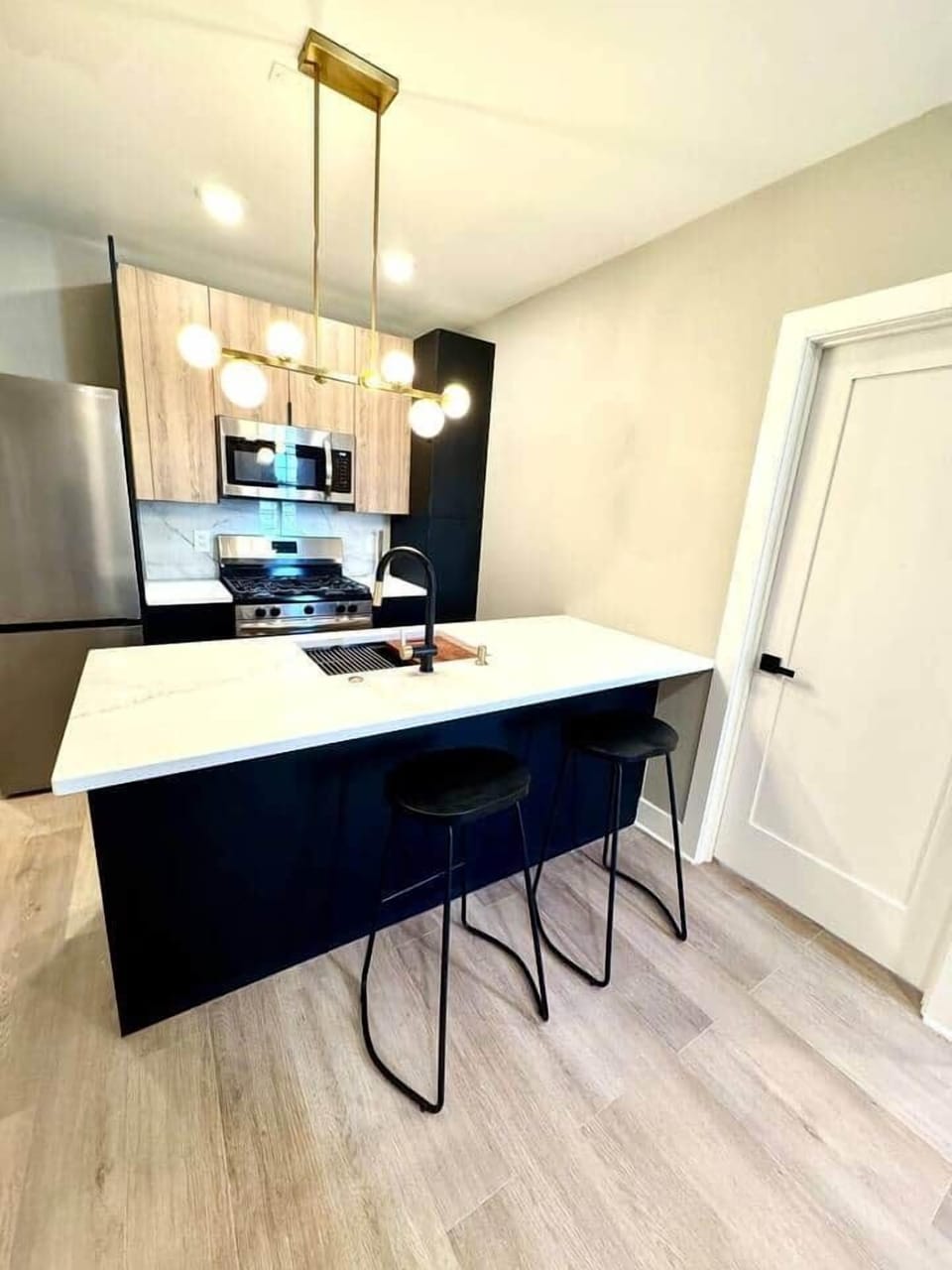 Fully equipped kitchen featuring a dishwasher, microwave, oven/stove, refrigerator, garbage disposal, dishes, and cookware, along with a granite countertop island and barstools.