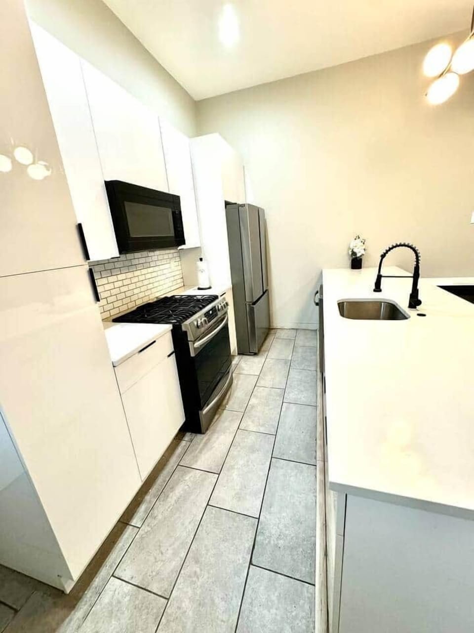This kitchen features a stainless steel stove with five burners and an oven, a 34-inch three-drawer refrigerator, a microwave, a dishwasher, a garbage disposal, a pantry, and ample drawer space for dishes, pots, and pans.
