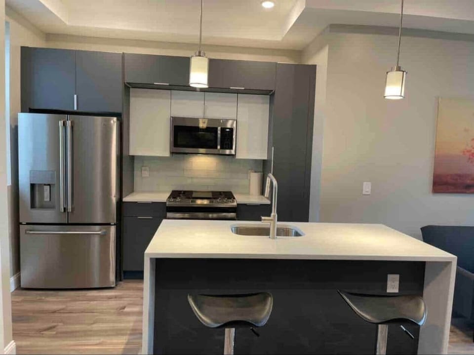 Fully equipped kitchen featuring a large stainless steel refrigerator, a dishwasher, oven, & a microwave.
The elegant granite waterfall island with bar stools, with all your everyday kitchen essentials.  
Also a Keurig coffee Mechine. 