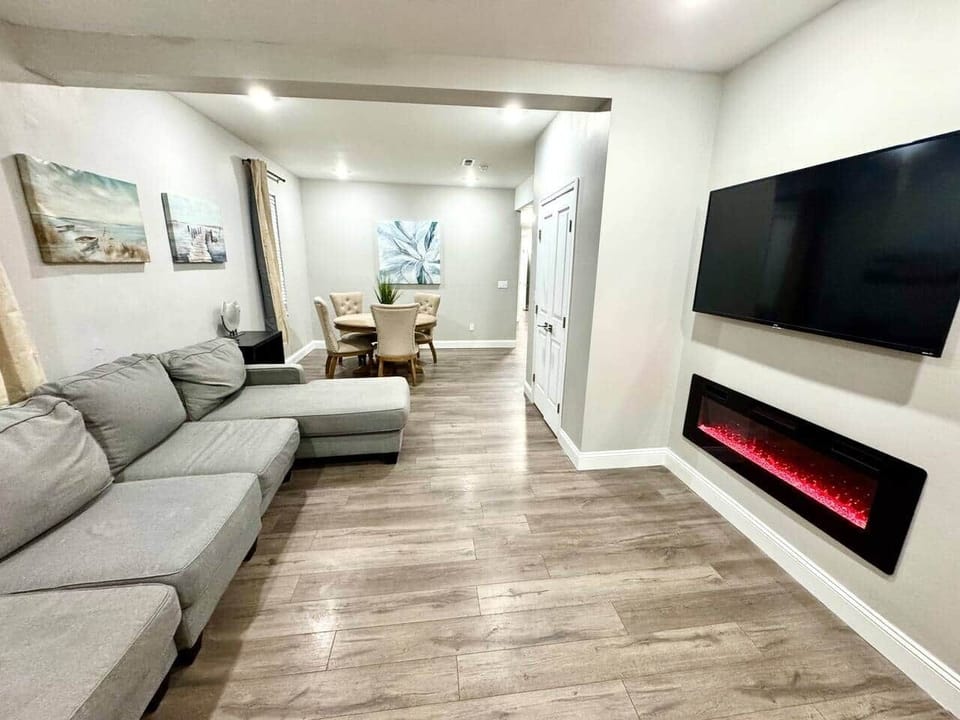 Spacious living room featuring a large sectional couch, flat-screen TV, and cozy fireplace, seamlessly connected to the dining area for an inviting and comfortable experience.