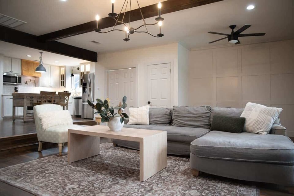 Relax in the stylish living room with a spacious sectional, soft textures, and warm lighting—steps away from the open kitchen and perfect for movie nights or morning coffee