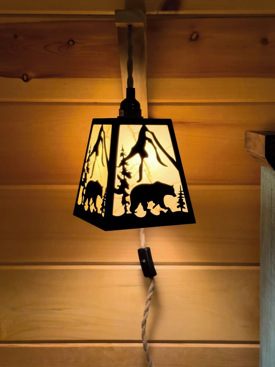 Bear-themed lantern adds warm, cozy cabin charm against wood walls.