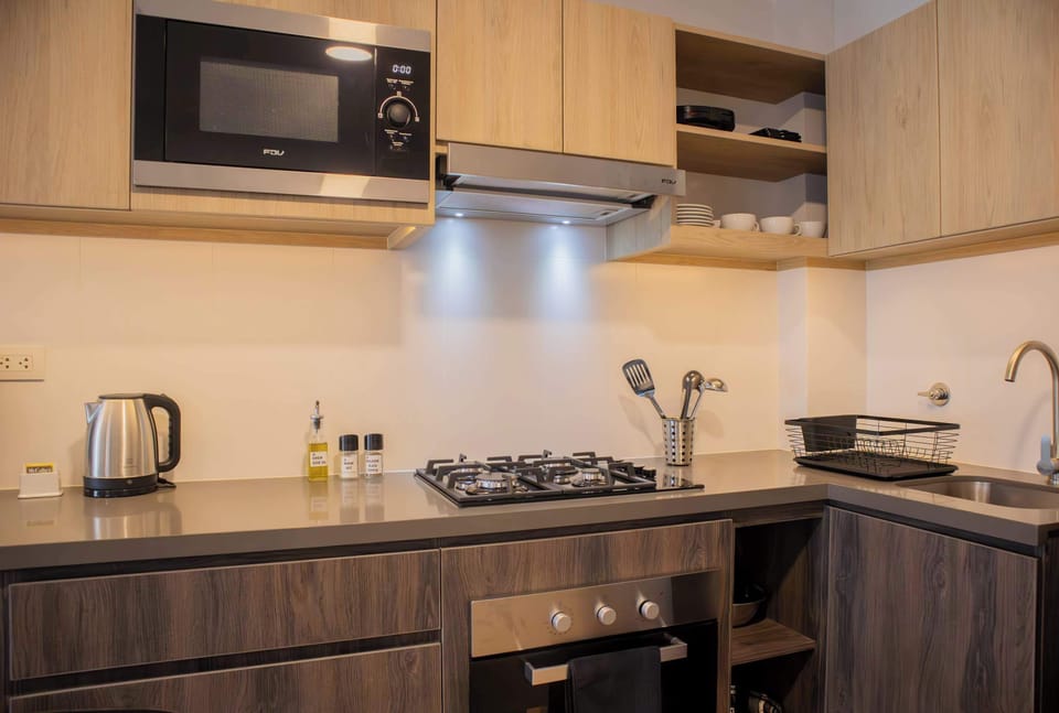 Close-up of stovetop, microwave, and wooden cabinetry in kitchen.