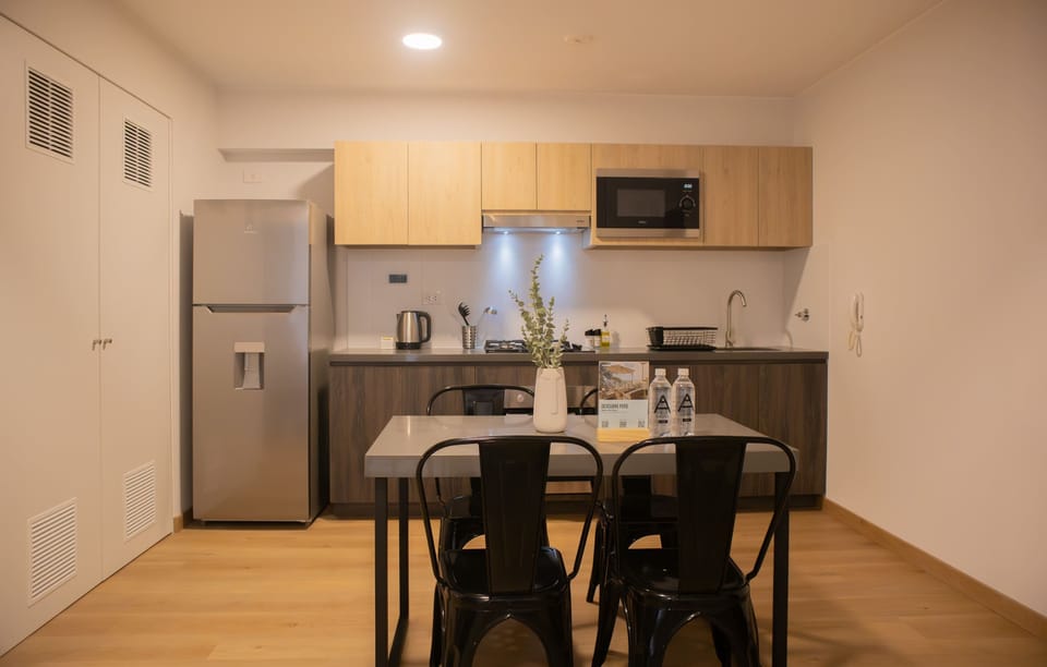 Wooden dining table with black chairs, part of an open layout connected to the kitchen.