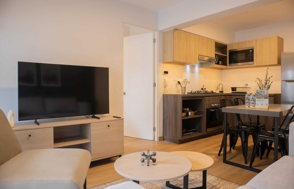 Stylish living room with a sofa, TV, and a dining area connected to a modern kitchen.