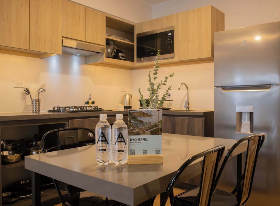 Modern kitchen with light wood cabinets, stainless steel appliances, and an organized countertop.