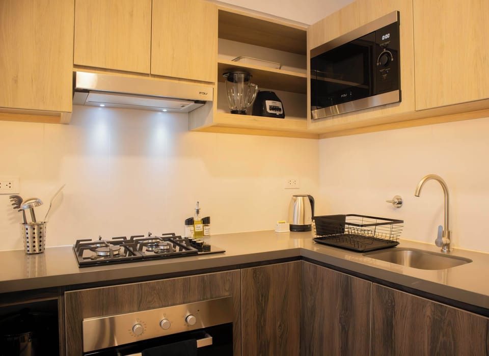 Modern kitchen with wooden cabinets, a gas stove, and a microwave, featuring a clean and organized countertop.