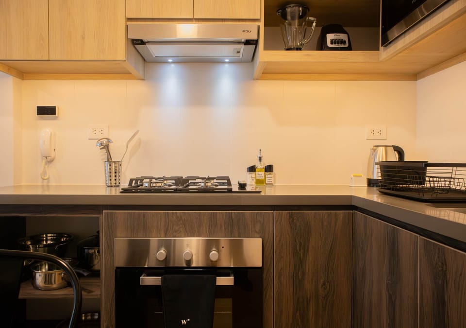 Fully equipped kitchen featuring sleek wood and stainless steel finishes, with clean countertops.
