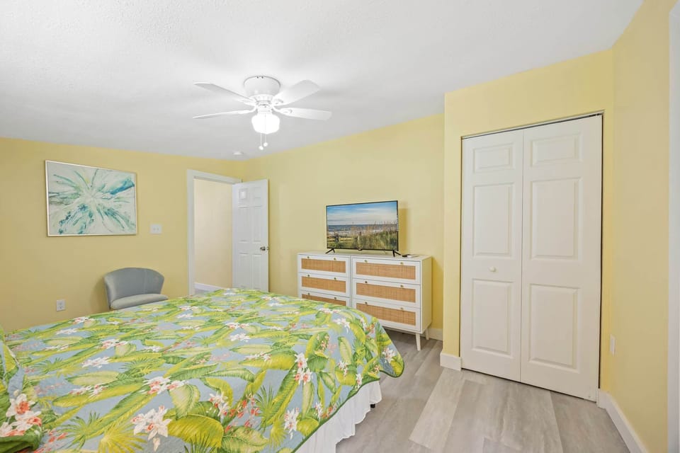 Bedroom with tropical bedding, a dresser, and a ceiling fan for comfort.