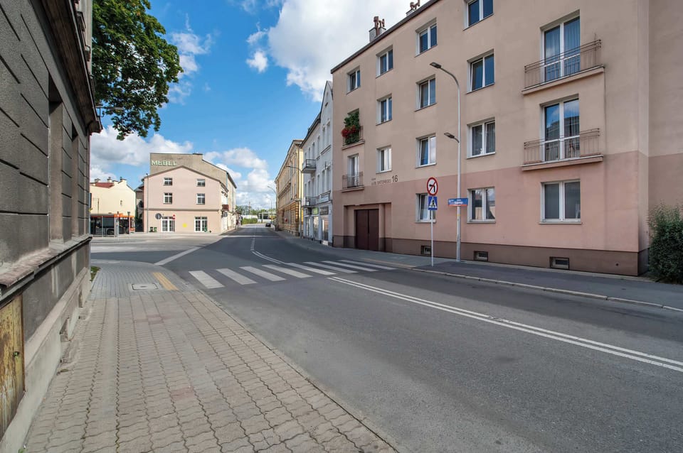 A street view in front of the building with sidewalks and neighboring buildings. The area appears calm and residential.