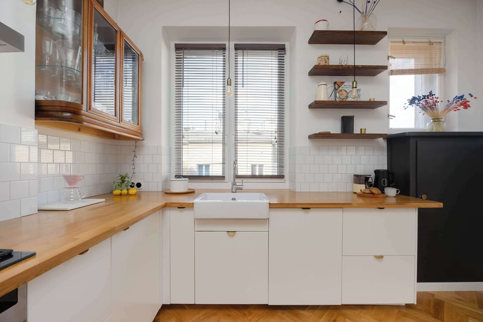 The bright kitchen with a wooden countertop and open shelves combines simplicity with style, offering a practical space for cooking.