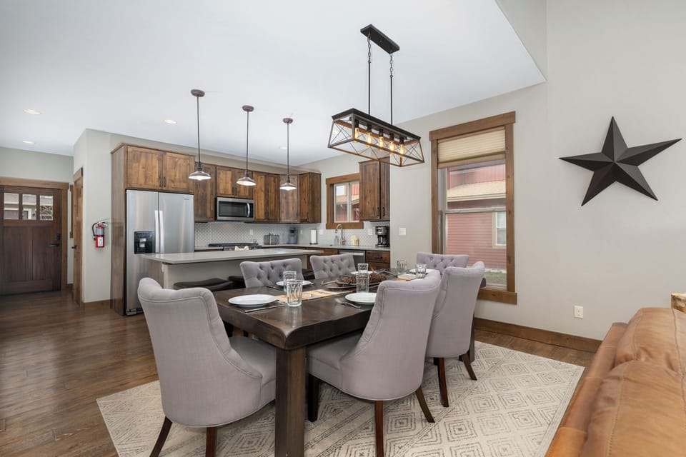 Gather around your elegant dining table in this open-concept space where warm wood tones and modern fixtures create the perfect atmosphere for memorable meals.