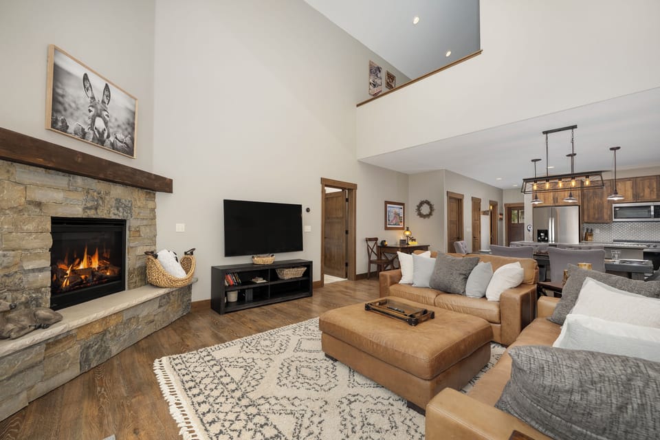 Unwind by your crackling stone fireplace in this open-concept living space, where leather seating and modern amenities create the perfect mountain retreat.