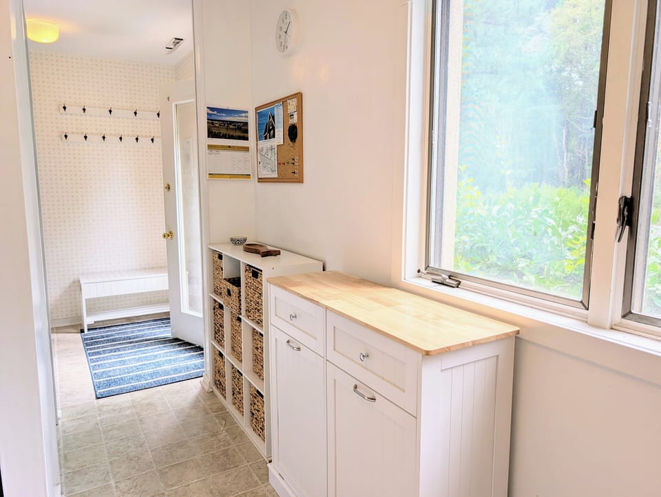 718D Treetop Lane - Mudroom Entry - The entryway is bright and functional, featuring light-colored flooring and white walls. It includes a built-in storage bench and a wall-mounted coat rack with multiple hooks, providing an organized space for beach gear and outerwear.