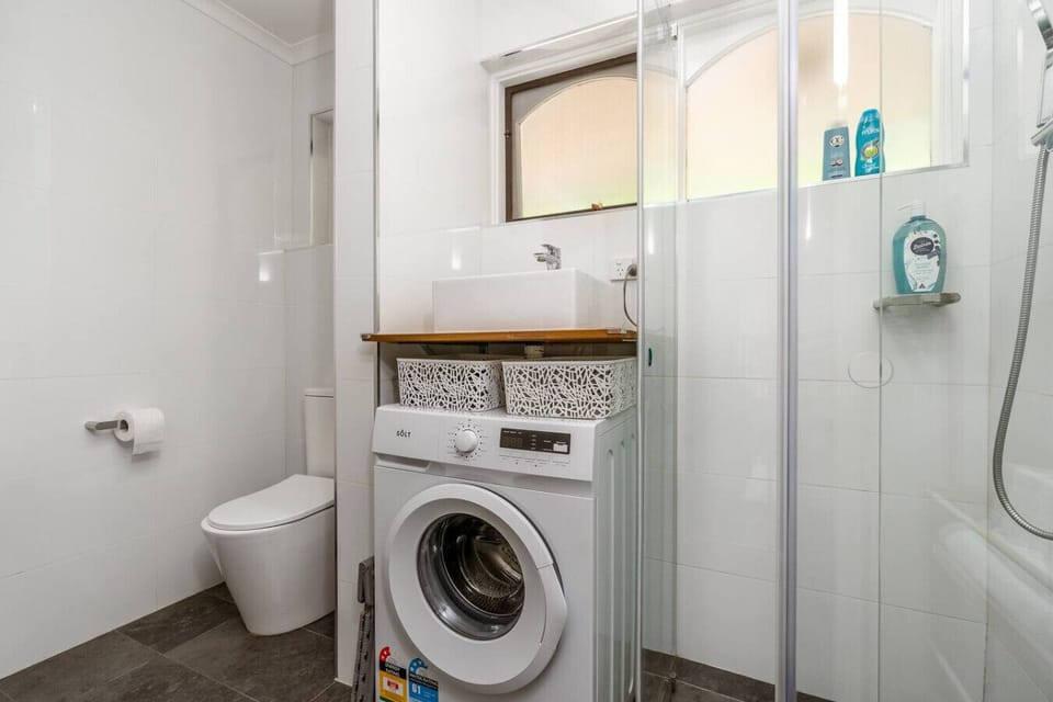 Fresh, organized bathroom featuring a stylish shower and efficient laundry setup.