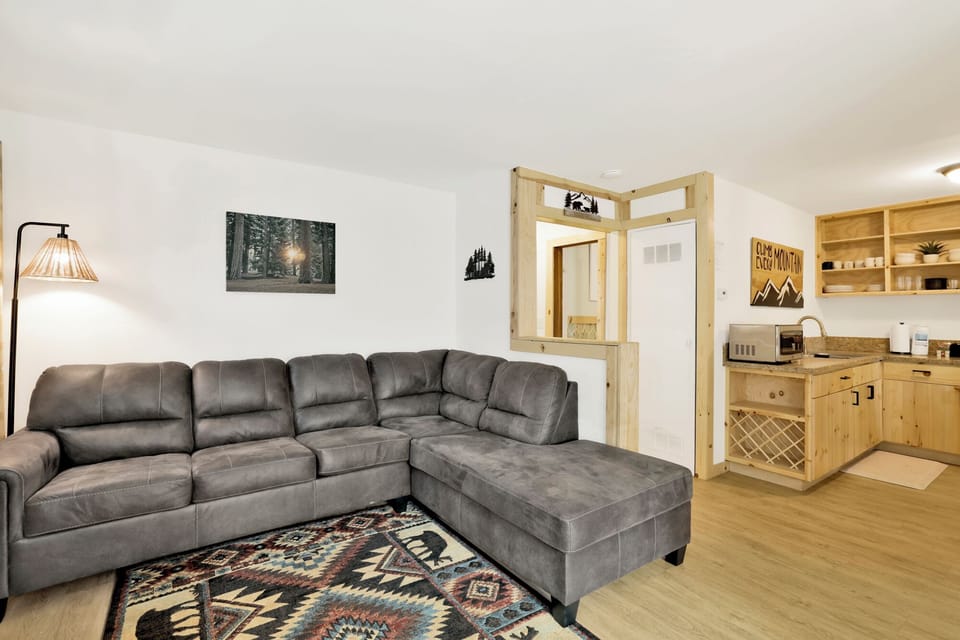 Cozy mountain living room with a stone fireplace, comfy seating, and smart TV—perfect for relaxing evenings, movie nights, and warm cabin vibes after outdoor adventures.
