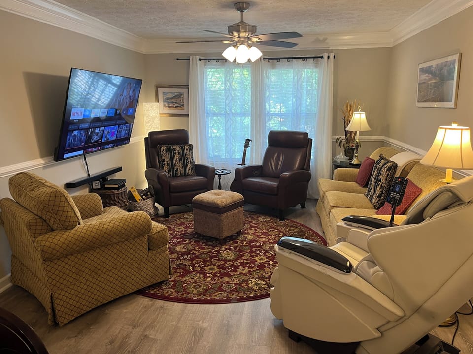 Living room features a 70 inch TV, seating for 7, & full body massage chair  