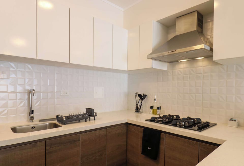 Focus on the gas stove area with a hood, kettle, and tiled backsplash.