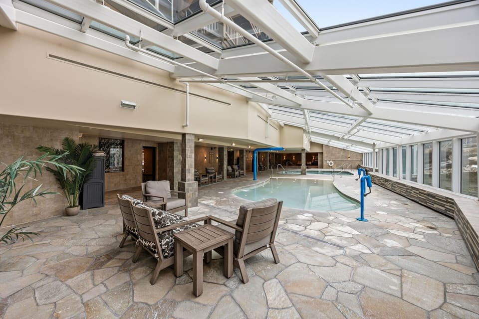 Pool-deck lounge with cathedral solarium and slope backdrop.