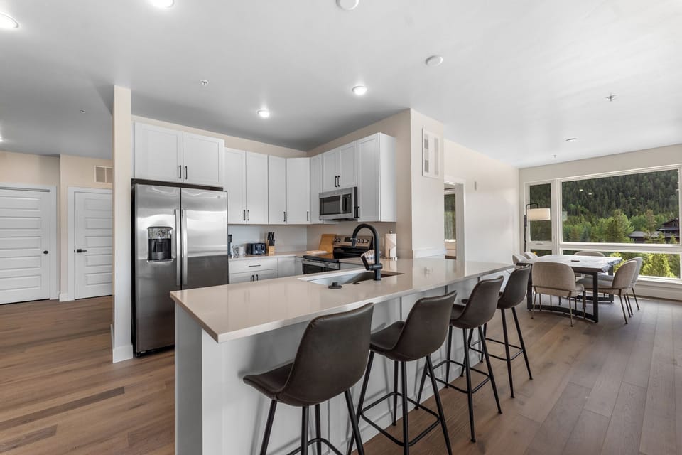 The full kitchen features stainless steel appliances and a breakfast bar with seating for four.