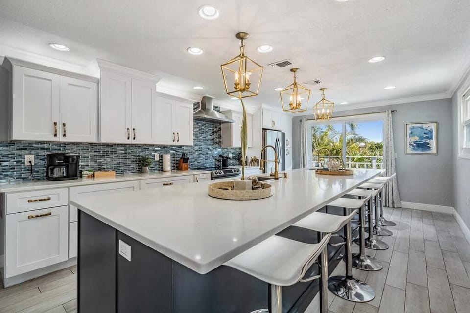 This gourmet kitchen boasts a massive quartz island with seating for 8, sleek cabinetry, stainless steel appliances & designer lighting. Bright, open, and perfect for cooking, dining & gathering with family and friends.