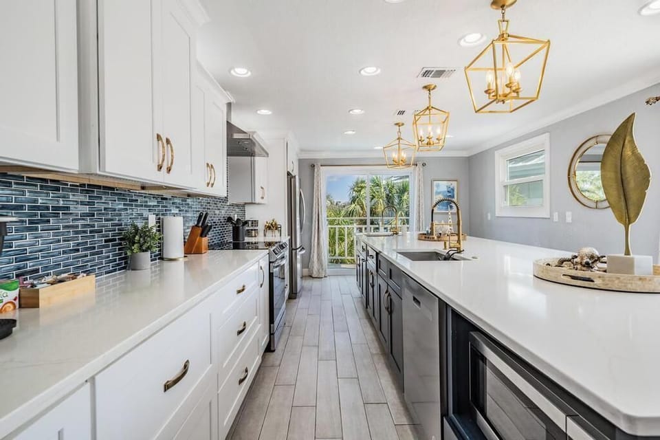 Stunning gourmet kitchen featuring quartz countertops, designer lighting, sleek cabinetry & stainless steel appliances. Spacious island with seating makes it perfect for cooking, entertaining, & creating unforgettable meals together.