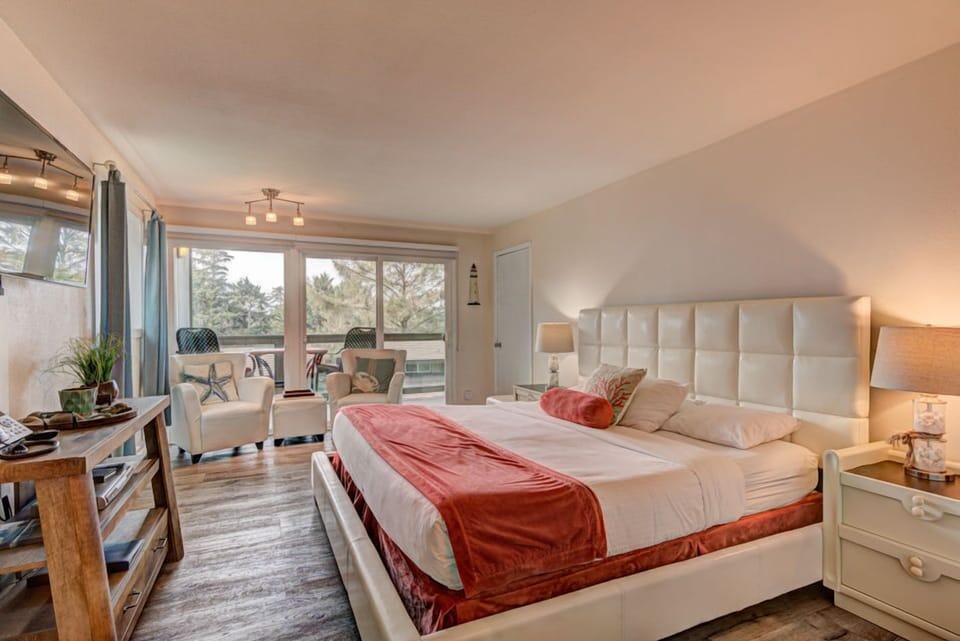 The inviting King Bedroom features a plush king-size bed, stylish furnishings, and large windows that open to a serene forest view from the balcony.