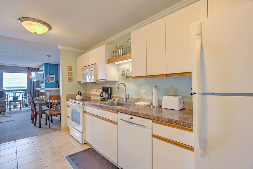 The full kitchen is equipped with all necessary amenities, providing guests with a convenient space to prepare meals while enjoying ocean views.
