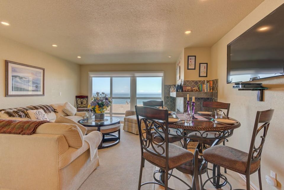 Bright and airy, the dining area adjacent to the living room features a circular table, perfect for enjoying meals while gazing at the stunning ocean views outside.