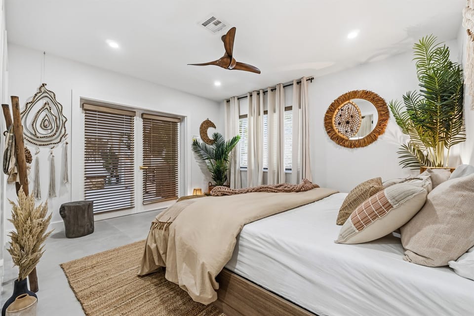 From the Luna Suite’s king bed, warm neutrals, artisan textures, and soft greenery flow seamlessly into the media sanctuary beyond. French doors frame sculptural TABU pieces and an inviting lounge, shaping a serene, connected retreat for unwinding.