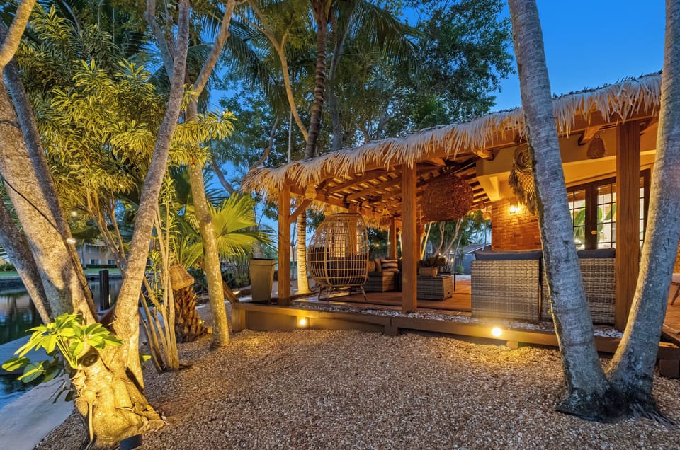 Illuminated palms and towering trees surround this terrace corner, creating a glowing jungle sanctuary—a serene Tabu space made for nighttime conversations, warm air, and quiet connection with nature. 