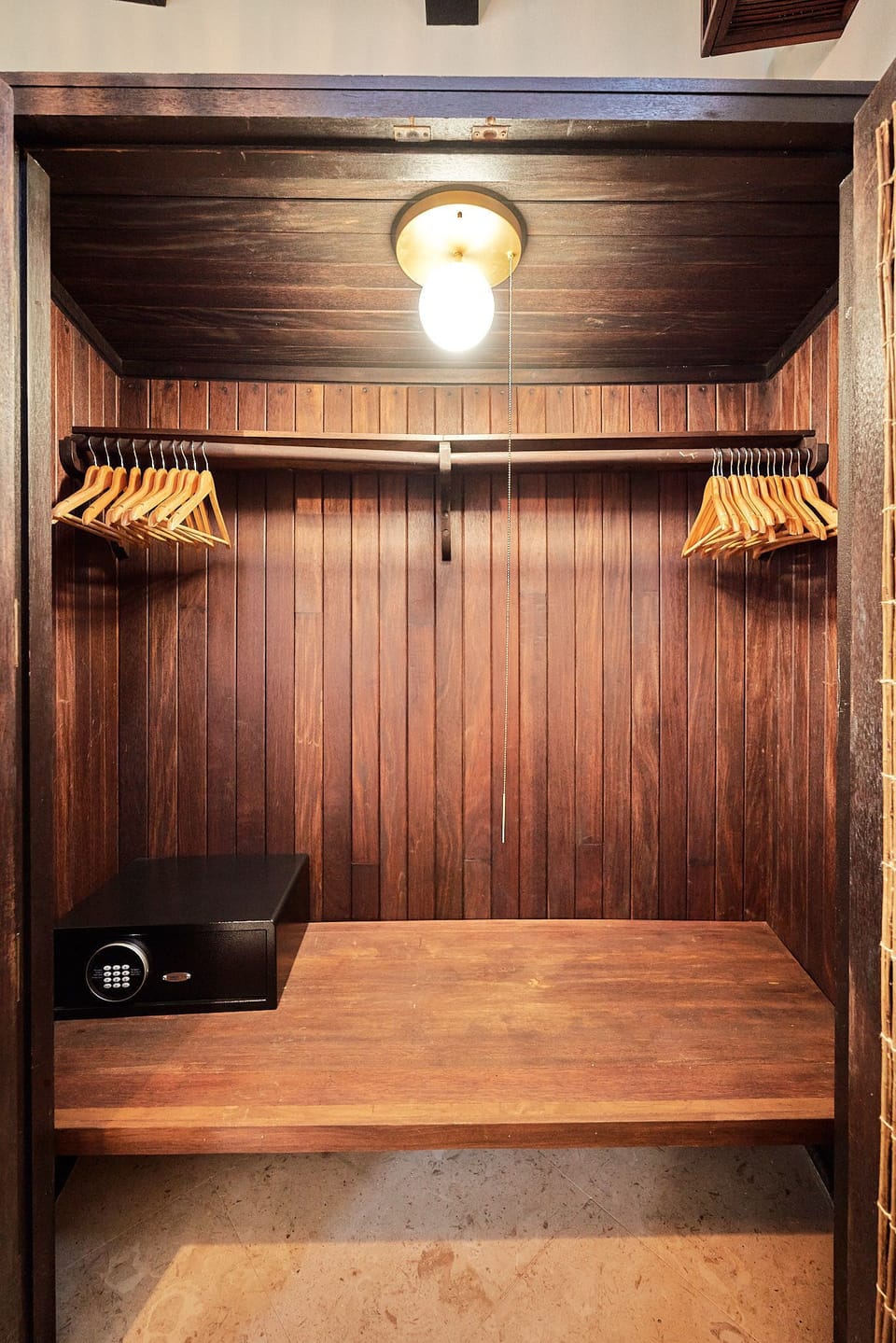 Dark wood closet with ample hanging space and built-in storage.