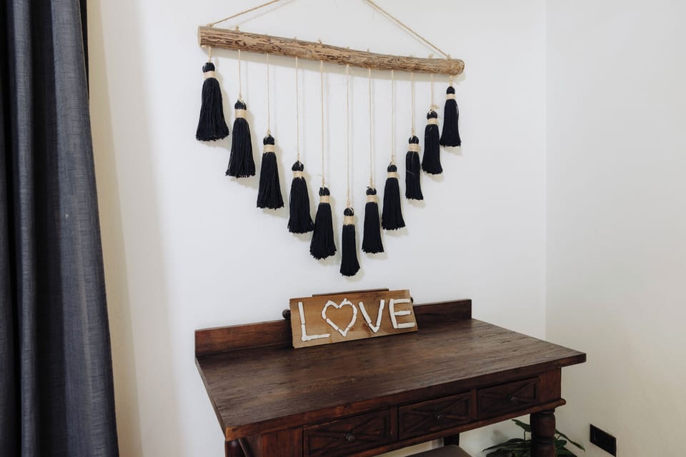 A closer look at the minimalist writing desk with handcrafted tassel wall art and cozy ambiance.