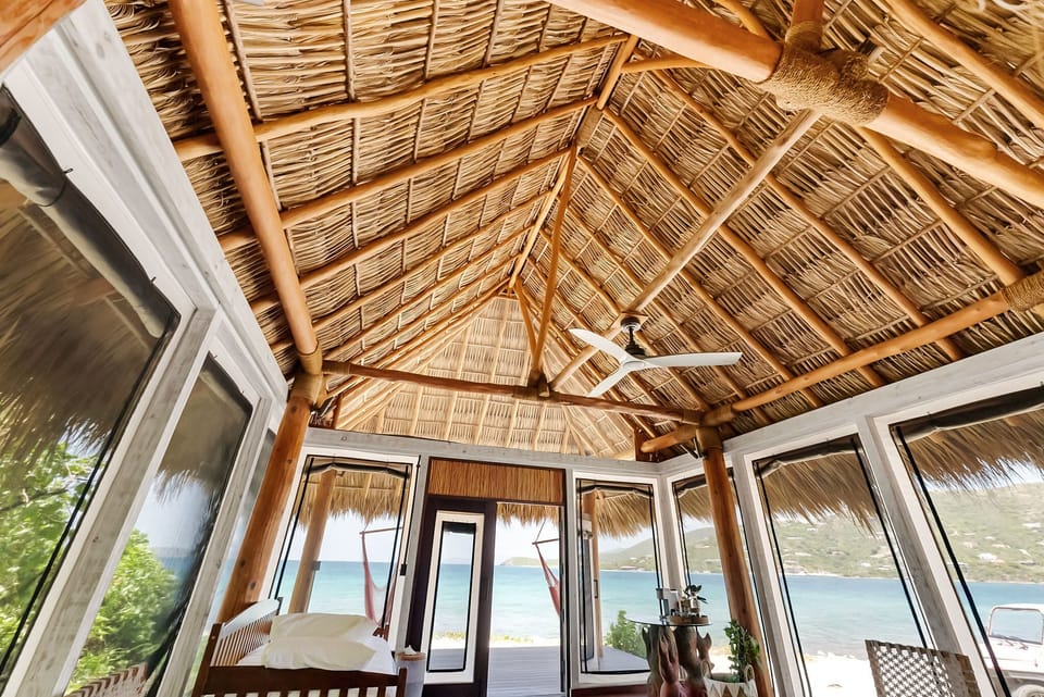 Thatched ceiling and screened windows bring the outside in for a breezy, open-air retreat.