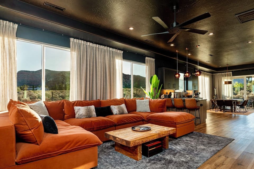Huge open concept living room with large windows overlooking red rock mountains