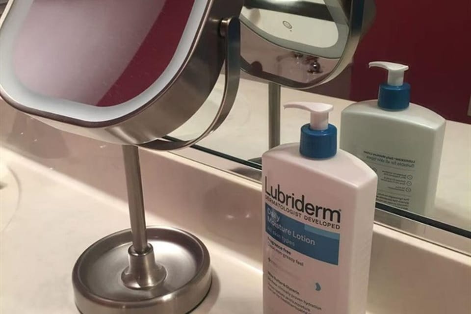 Bathroom vanity with mirror, lotion, and daily essentials provided