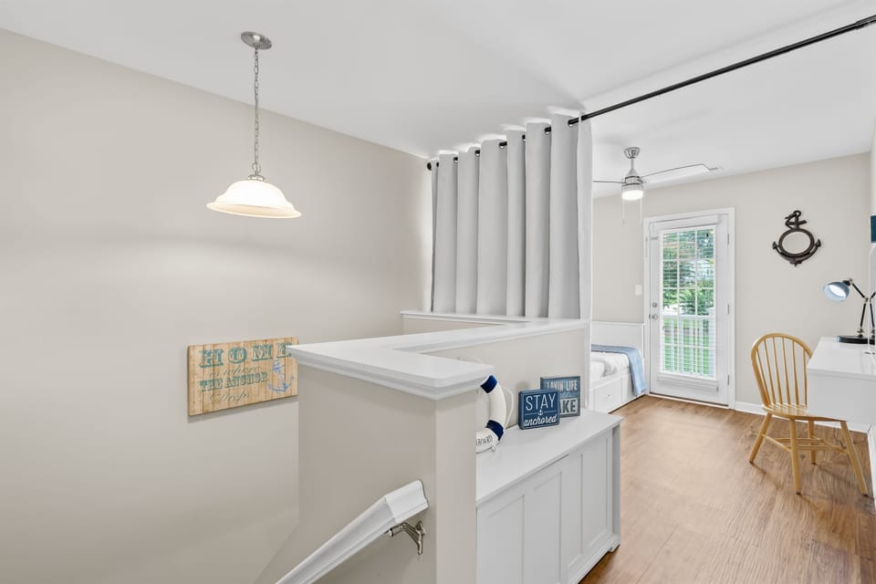 Landing area near the stairs with a desk nook and chair by the window.