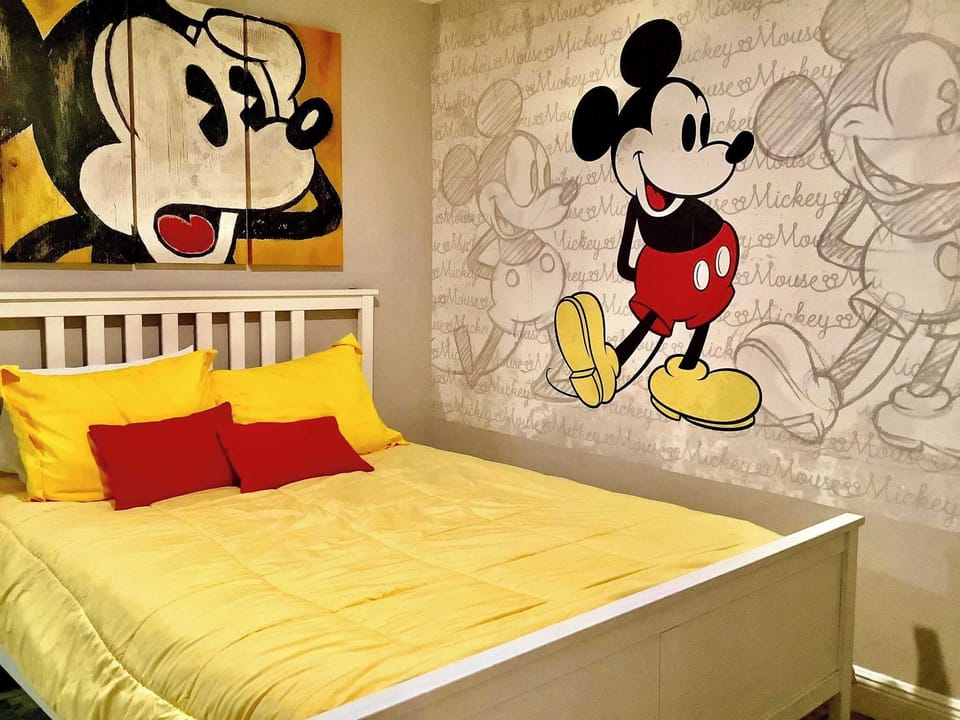 Family-friendly bedroom featuring vibrant Mickey Mouse wall art and cozy bedding.
