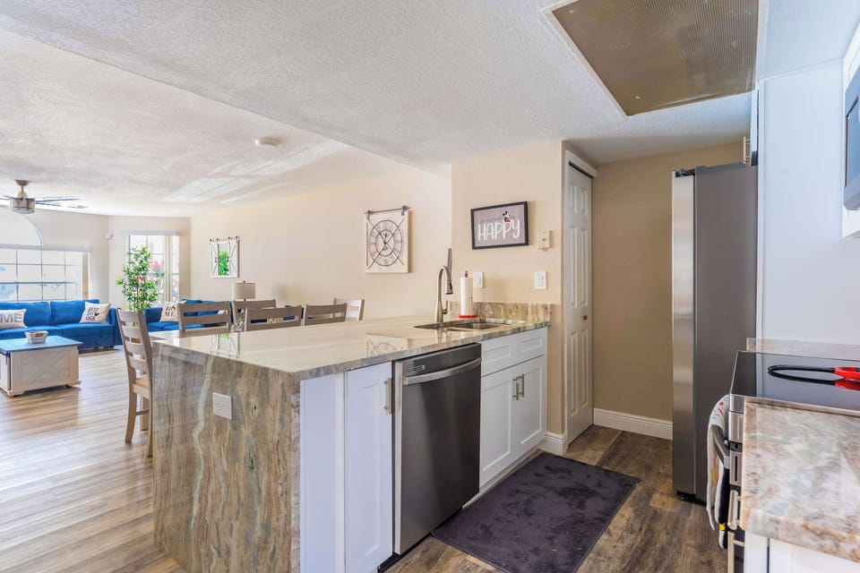 Open kitchen with a large marble island and stainless steel appliances overlooking the living area