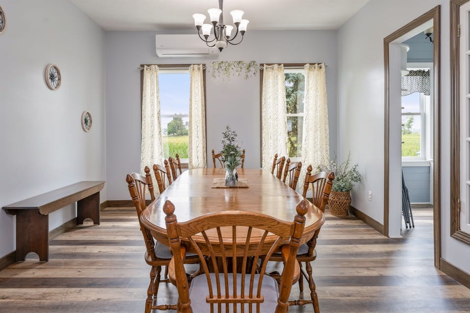 Bright and airy dining space featuring large windows, elegant curtains, and a spacious wooden table perfect for family meals or gatherings.