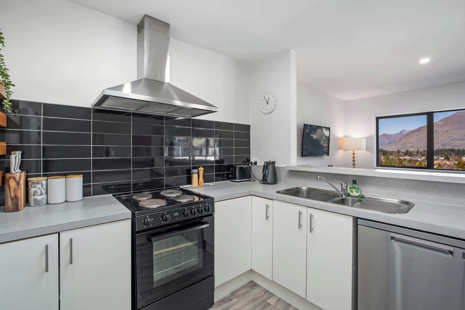 Well-equipped kitchen with essential appliances and black tile splashback