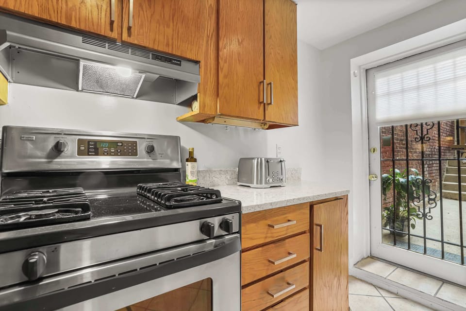 Kitchen with a view of the oven, range, stove, toaster, storage, and door to the outside. 