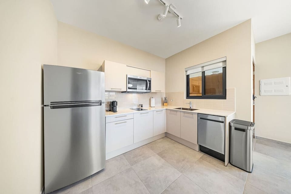 Sleek lines and modern efficiency define this beautiful L-shaped kitchen. Equipped with a full-size stainless steel refrigerator and ample storage space to make cooking an absolute breeze.